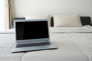 bed with blank screen notebook at bedroom.