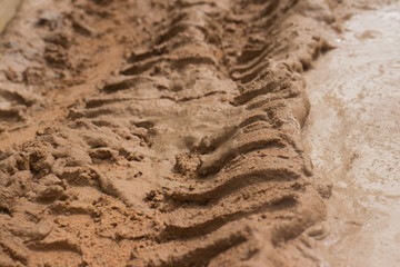 Ground level view horizontal ECU  muddy jungle road with pool of mud and knobbed tire tracks
