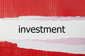 investment word written under torn paper. 