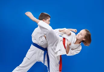 Photo sur Plexiglas Arts martiaux With red and blue belt the children are beating  karate blows