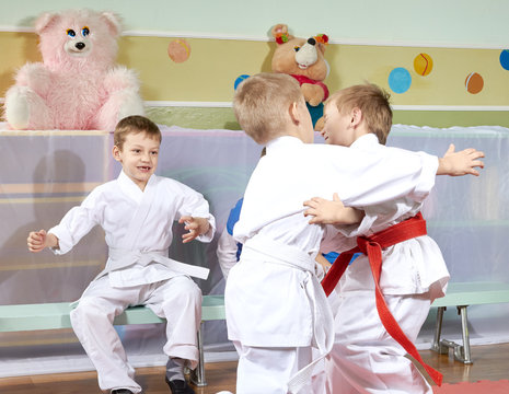 Two boys are trained judo sparring before other athletes