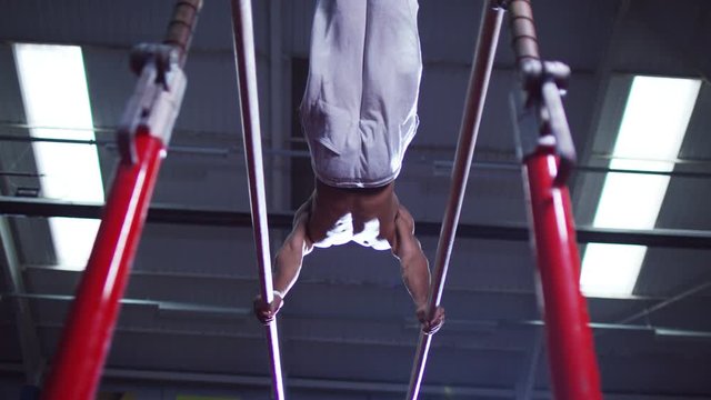  Professional male gymnast training on parallel bars at the gym.