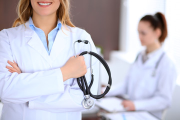 Doctor holding a stethoscope in his hand , against the background of another doctor