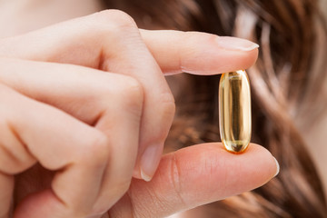 Woman hand showing Omega-3 capsule
