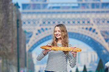 Girl with traditional French baguette near the Eiffel tower