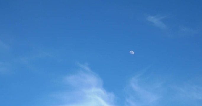 Moon Visible In Daylight Blue Sky With White Soft Clouds
