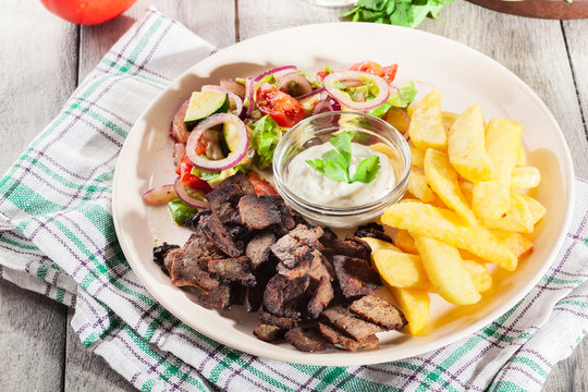 Grilled meat with French fries and fresh vegetables