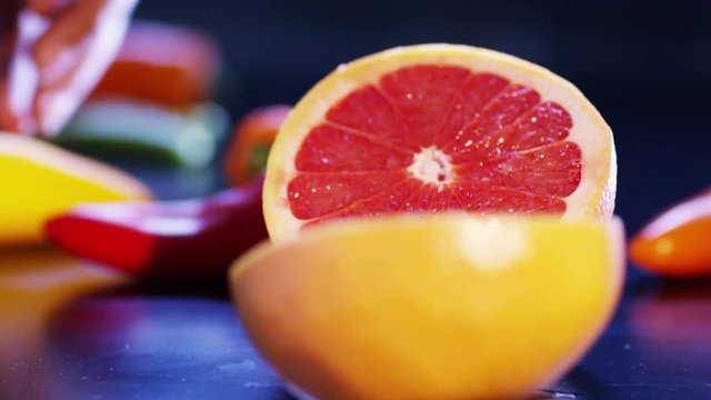  Close up on hands cutting a fresh pink grapefruit into 2 pieces