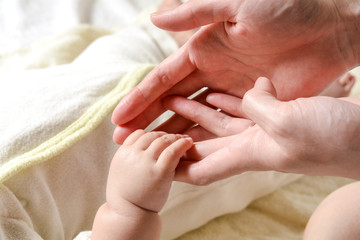 お母さんの指を握る赤ちゃんの手