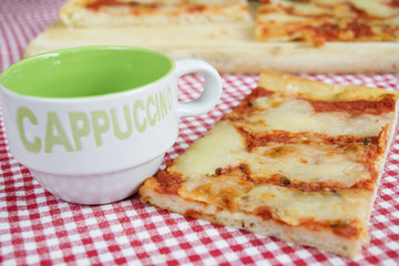 slice of margherita pizza with cup of cappuccino