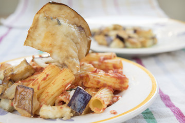 pasta alla norma with dish of eggplants in evidence