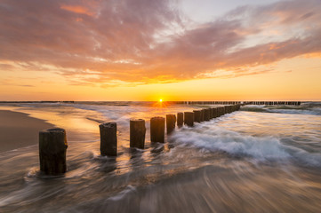 sunset over the sea, beach, beautiful sky and the waves breaking on the breakwater
