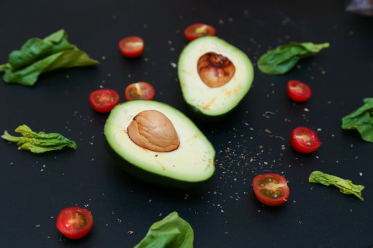 Fresh spinach, tomato and avocado on black background.