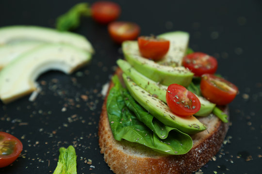Close up of toast with spinach leaves, avocado and tomaties.