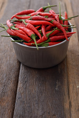 Red Chili pepper in bowl on wooden table, vertical. Selective focus