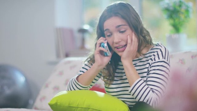  Upset young girl talking on mobile phone at home