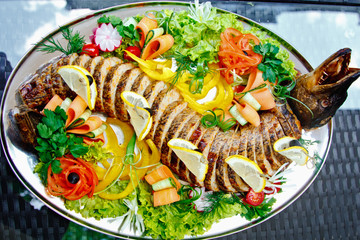 Stuffed pike decorated with vegetables and fruits with the greens. Very beautiful restaurant dish