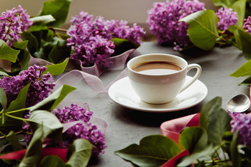 Beautiful background with a Cup of hot coffee with lilacs