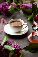 Beautiful background with a Cup of hot coffee with lilacs