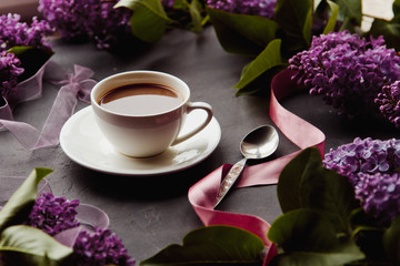 Beautiful background with a Cup of hot coffee with lilacs