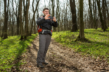 Man hiker taking photo with smart phone in forest