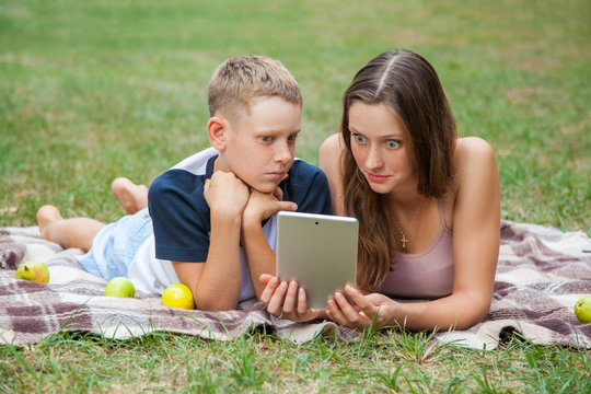 Young sister and brother lying down and work with tablet