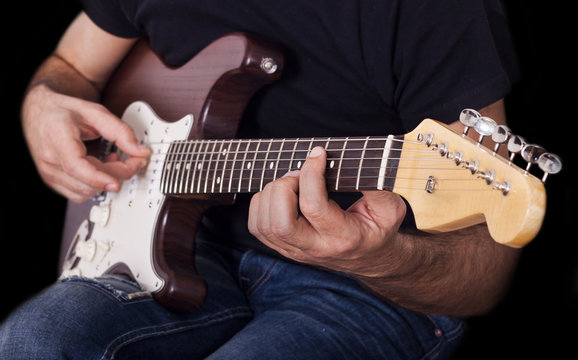 Man playing electric guitar on black background