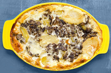Potatoes with mushrooms, baked in sour cream, blue wooden background