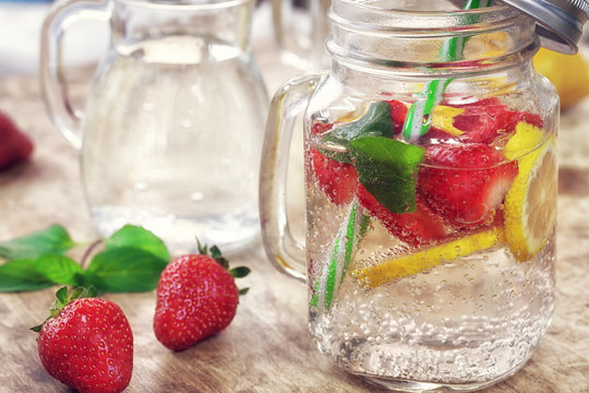 Detox Infused water with lemon, strawberry and mint on wooden background