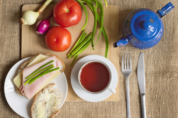 Rustic breakfast with bread and butter, chives, tomatoes, young onions and a cup of tea. Diet concept.