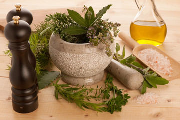 various spices on a wooden table with mortar, pestle and mills.