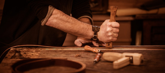 Leather goods craftsman at work in his workshop - obrazy, fototapety, plakaty