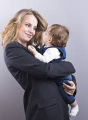 Beautiful blonde with her little son on hands. Happy business woman.
Family life. Children. Young mother
