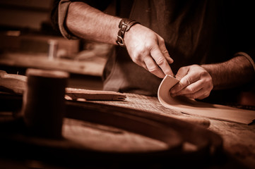Leather goods craftsman at work in his workshop - obrazy, fototapety, plakaty