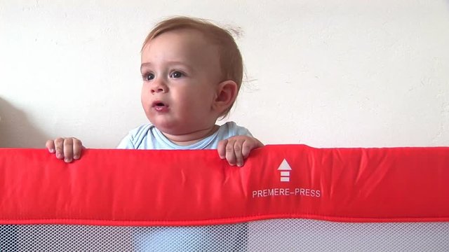Baby boy standing in his bed, looking around
