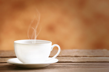 Cup of coffee on table on brown background