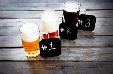 Glasses with different sorts of craft beer and numbering on wooden table. Retro stylization