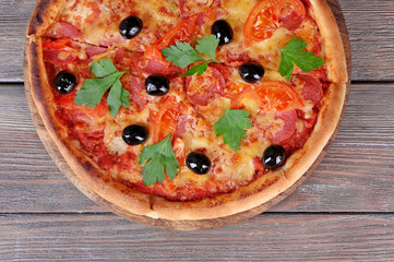 Delicious Italian pizza with black olives on wooden table background