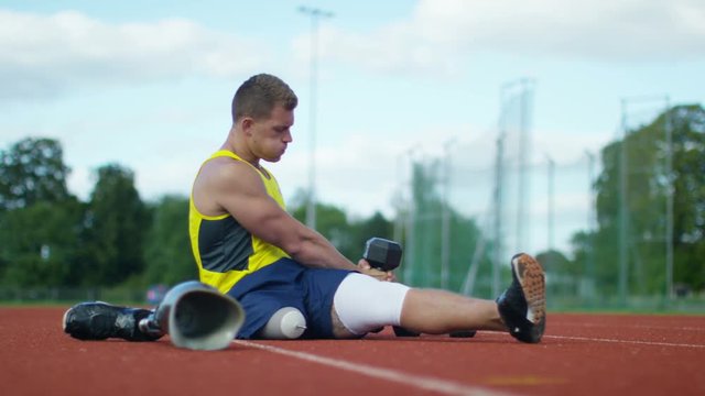  Disabled athlete with prosthetic leg working out with weights @ running track