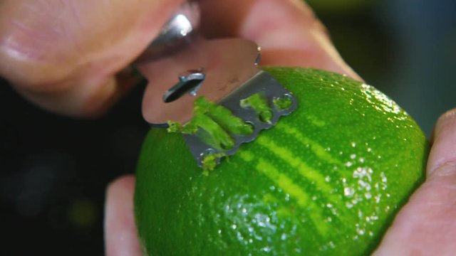Extreme close up of zest being scraped from a juicy lime