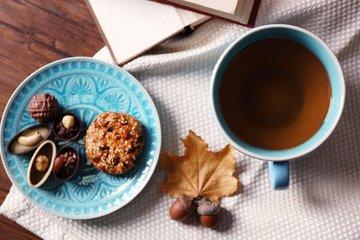 Cup of tea with autumn decor on wooden table.