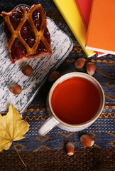 Cup of tea with autumn decor on wooden table.