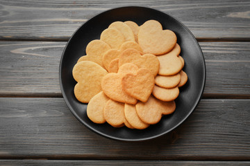 Heart shaped biscuits in black plate on wooden background