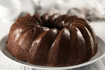 Chocolate cake on plate on white wooden background