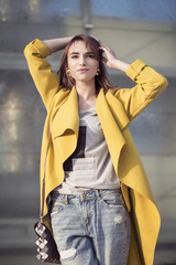Young woman in a yellow coat on a background of city