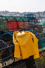 Trawlerman's protective oilskin smock, and lobster pots in the harbour. In Scarborough, England. On 5th May 2016.