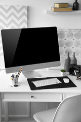 Modern wide screen monitor on white table in room interior