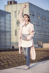 A young woman in a pink coat on a background of the city