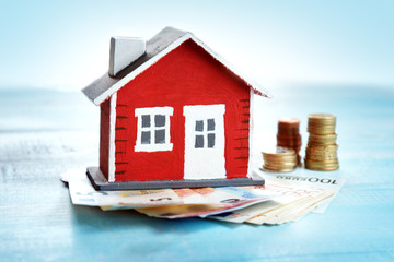 Red house model on wooden background with banknotes and coins - Powered by Adobe