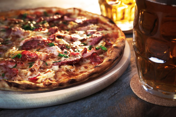 Delicious pizza  and glasses of beer are on wooden table, close up